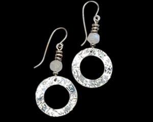 Earrings made with moonstone and silver beads and a pewter washer dangle that has been shaped into a wave pattern