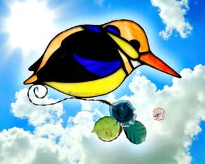Black-backed Kingfisher suncatcher in direct sunlight- made of black, yellow, orange and dark blue glass. With lamp worked leaves and flower accents.