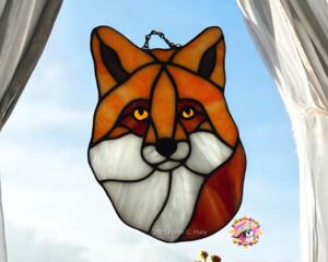 Fox Face Portrait Stained Glass Suncatcher by Robin C. Hary- made of shades of orange, red, and white glass.
