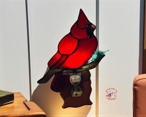 Cardinal Stained Glass Night Light- sitting on a brown glass branch with a green lampworked leaf, cardinal is made of bright red glass.