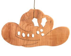Handmade wooden Christmas tree ornament shaped like a cowboy hat, featuring a sprig of holly tucked into the hat band, star-shaped leaf cutouts, and round berry accents.