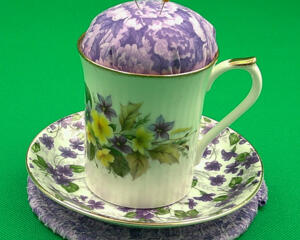 This shows the pincushion with the saucer aka bobbin holder sitting on top of the trivet. It's about 5 inches high by 5.5 inches wide.