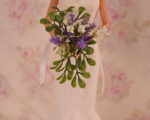 Picture of a 11.5 inch doll holding a rustic purple, white, and green wedding floral bouquet 1:6 Scale