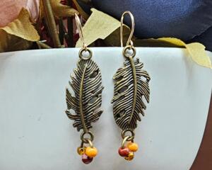 Handmade brass leaf earrings with glass seed beads on a jump ring and 14K gold earring wires, 2 inches long.