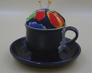 Looking at the front of the pincushion/bobbin holder, it's easy to see the lace on the mug and the colors of the flower of the pincushion.