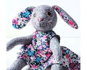 Handmade gray wool rabbit doll named Josie wearing a floral cotton dress — soft, upcycled, and eco-friendly heirloom toy.