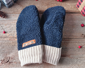A cozy pair of teen, small woman’s handmade mittens crafted from fluffy blue fleece with tan beige ribbed cuffs; handmade and winter ready.