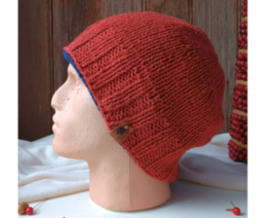 Profile image of slouchy rust wool knit hat with navy trim and small leather tag, styled on mannequin head.