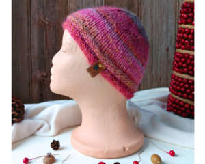 A side view of a handmade baby hat in a pink & purple wool blend yarn. Great for winter holiday gifting for newborn babies 0 to 12 months.