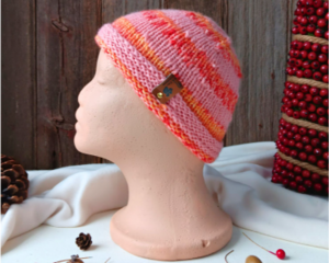 A handmade baby hat in a pink & yellow wool & acrylic yarn. Great for winter holiday gifting for newborn babies 0 to 12 months.