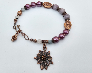 Handmade bracelet with purple beads, lavender stones, copper leaf beads, and a floral copper charm and copper pinecone charm