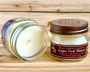 Pine and Bayberry scented soy candle in 4oz mason jar. One jar standing up with lid on and one jar on its side with lid off.