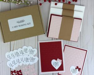 A handmade card kit to make 12 embossed valentine's cards, with pink and red cardstock, "love you" stamped sentiments and cardstock bows.
