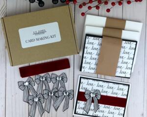 A handmade card kit with love patterned scrapbook paper, red velvet ribbon, die cut black and white bows and cards and envelopes for 6 cards