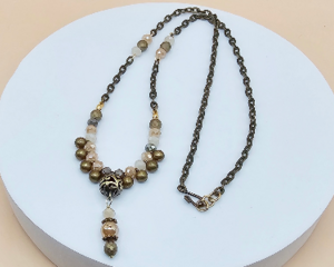 Vintage inspired handmade antiqued brass necklace with peach crystals, glazed agate beads, hematite accents, and a decorative center drop.