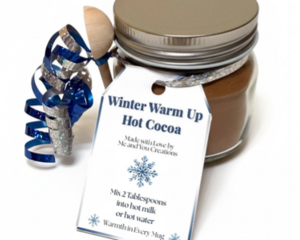 Handmade Winter Warm Up hot cocoa jar with reusable glass jar, wooden spoon, blue ribbon, and winter tag on white background
