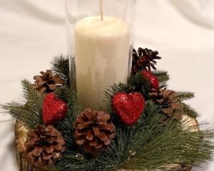 Handmade rustic wood slice candle centerpiece with pine greenery, pinecones, red heart accents, and glass hurricane candle holder