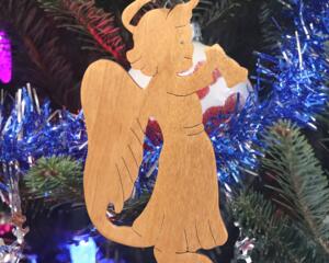 A handmade wooden Christmas ornament in the shape of a cheerful angel, featuring a halo, wings, and a raised arm ringing a bell, hand-cut from solid hardwood and finished with clear shellac.