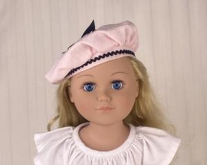 Blonde 18 inch doll wearing a pink beret/hat with black trimmings