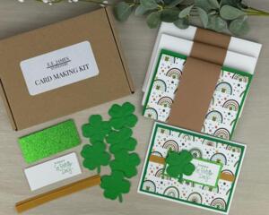 A St. Patty's Day card making kit with clovers, gold ribbons, stamped sentiments and glitter mats to make 6 greeting cards.