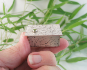 Miniature Silver Trinket Box with peridot gemstone, held by fingers