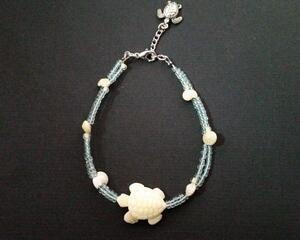 Turtle bracelet with glow in the dark beads, vintage shells, extender, and a silver turtle charm. Turtle's shell and underside has texture.