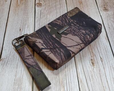 front view of a camo wristlet with gunmetal hardware and a gunmetal Bass Creations logo.