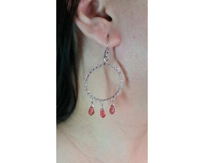 Person models a bright pink and silver wire wrapped dangle earring.