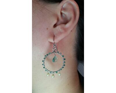 Green and cream wire wrapped dangle hoop earrings modeled on a person.
