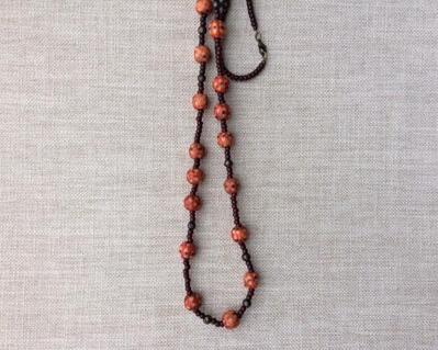 Beaded necklace featuring faceted pearls and decorative orange wooden beads