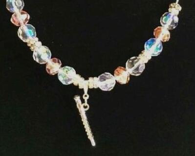 Elegant clear and pink glass beads with silver tone spacers  placed on a silver plated chain with a 3D flute pendant charm. This necklace may be worn by the younger flutist or older.  The flute has excellent 3D design and looks like a real flute.  The beads give all numerous colors. Delicate or petite this is lovely.