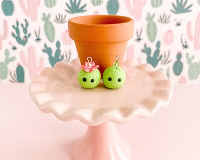 fireflyFrippery Cute Cactus Charms in front of Miniature Terra Cotta Pot on Pink Display