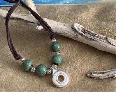 A year around winner for this necklace design.  We added green ceramic beads with brown speckles and then put filgree beats for accenting, The pendant is an open hole silver flute key and please us people will talk about the beauty of this jewelry item.