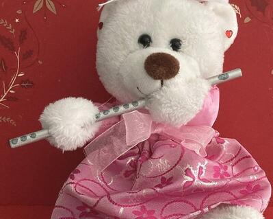 For the young flutist this bear is the cutest Valentines Day gift they can receive.  A white bear with a brown nose, rhinestone pierced earrings, white ribbons with red glitter hearts for accenting.  Little rhinestone hearts on bottom of feet, silk like fabric with hints of red, and last but not least she is playing a silver wood flute. May be purchased with or without flute.