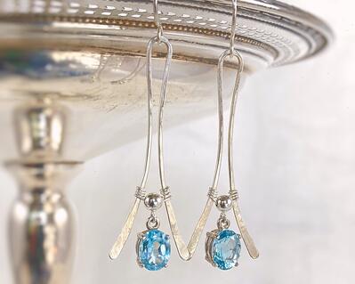 This is a gorgeous pair of blue topaz earrings featuring faceted, prong-set blue topaz gemstones that dangle from handmade sterling silver wishbone frames. By MariesGems.