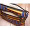 Top view of a medium sized makeup pouch with two zipper compartments, golden yellow, green and blue  Kente printed fabric, and ivory pearl waterproof canvas lining.