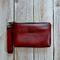 front view of a  burgundy marbled faux leather makeup bag with gunmetal hardware and a wristlet strap.