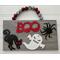 Gray oak laminate plaque, wood cutouts hand pained.  Crystal rhinestones red for cat, clear for ghosts, and green on spider.  Boo written in bold red.  Measurements: 9" x 5" x 1/2".