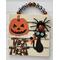 Five slat boards are attached to create a one-of-a-kind Halloween plaque.  A large pumpkin has a gray gemstone on his head and his friend, the black cat, is wearing a orange bow, has green moveable eyes and unfortunately for her she is wearing an orange and black spider her head.  Plaque has plaid buffalo wood beads for the wall hanger.  Measurements are 1" W x 7" H