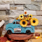 Teal truck filled with sunflowers and acorns.
