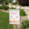 Pink and yellow spring gnome garden flag in a landscape setting