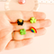 Set of four stud earrings - a four leaf clover, pot of gold, half a rainbow and three leafed shamrock - in between the fingers of a beige hand