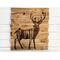 Wood wall art featuring a deer with antlers. The inside of the deer has a pine forest drawing.  The deer is wood-burned onto an old fence. 