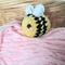 Yellow Bumblebee Plushie displayed on pink yarn in front of a fruit basket