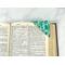 A green batik cotton fabric corner bookmark with a modern pattern.  It's shown on the corner of a page in a book to help mark your spot.