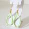 Green opal beaded dangle earrings, with gold crystal accents, shown on a display stand.