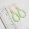 Green gemstone dangle earrings, with gold crystal accents, shown next to a ruler.