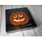 Photo of small square canvas painting of glowing jack o'lantern pumpkin with swirling eyes and a starry sky in the background