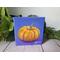 Photo of small square canvas painting of orange pumpkin with purple blue background