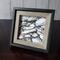 Photo of small drawing of rocks in black and white ink, framed with a black and grey frame